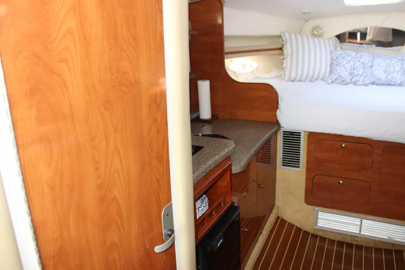 Slide: The Image of 2004 Rinker 342 Express Cruiser interior with wood cabinetry, bed, and compact kitchenette. - 18