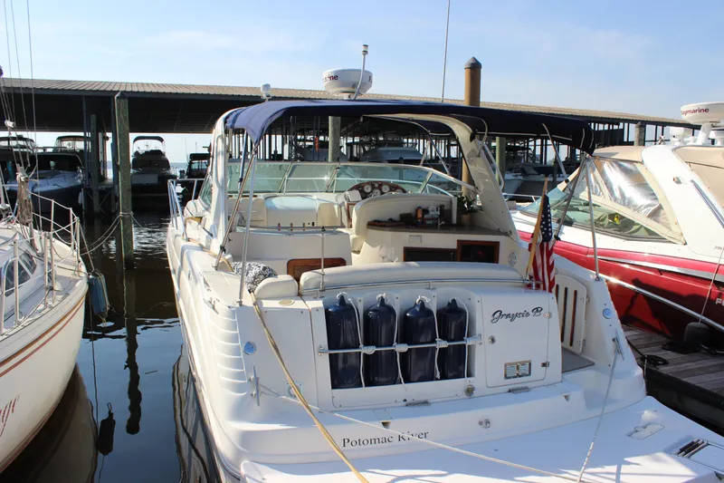 Slide: The Image of 2004 Rinker 342 Express Cruiser docked at marina, rear view with canopy and American flag. - 2