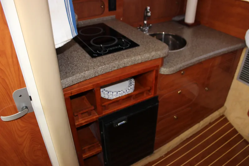 Slide: The Image of 2004 Rinker 342 Express Cruiser kitchen with stove, sink, and wooden cabinetry. - 20