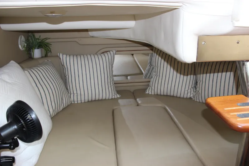 Slide: The Image of 2004 Rinker 342 Express Cruiser cabin with striped pillows and cozy seating area. - 28