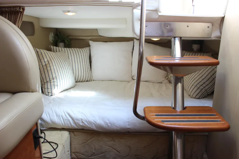 Slide: The Image of Cozy cabin interior of 2004 Rinker 342 Express Cruiser with striped pillows and wooden steps. - 30