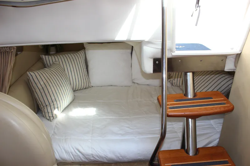 Slide: The Image of 2004 Rinker 342 Express Cruiser cabin with cozy bed and striped pillows. - 32