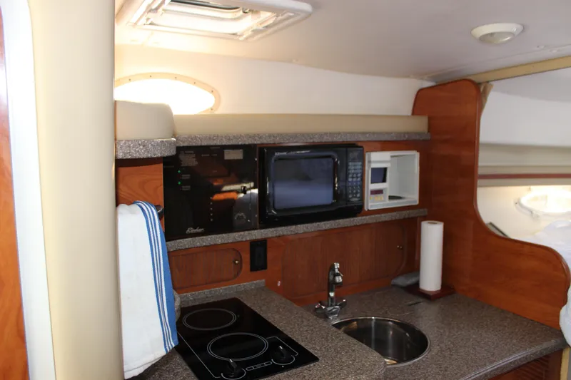 Slide: The Image of 2004 Rinker 342 Express Cruiser kitchen with microwave, stove, and sink. - 21