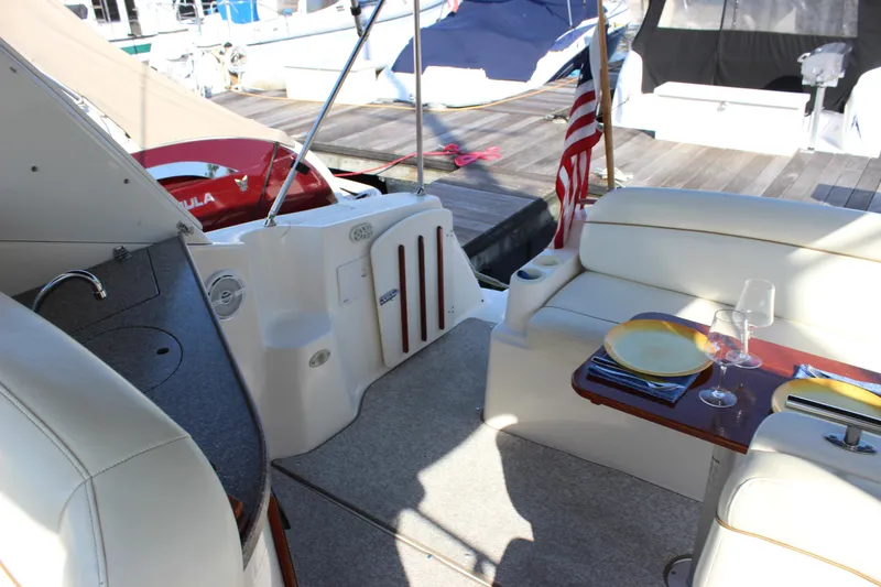 Slide: The Image of 2004 Rinker 342 Express Cruiser interior with seating, table, and dock view. - 15