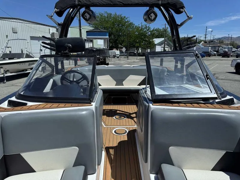 Slide: The Image of 2017 Moomba Helix boat interior with dual windshields and wooden flooring in a marina setting. - 23