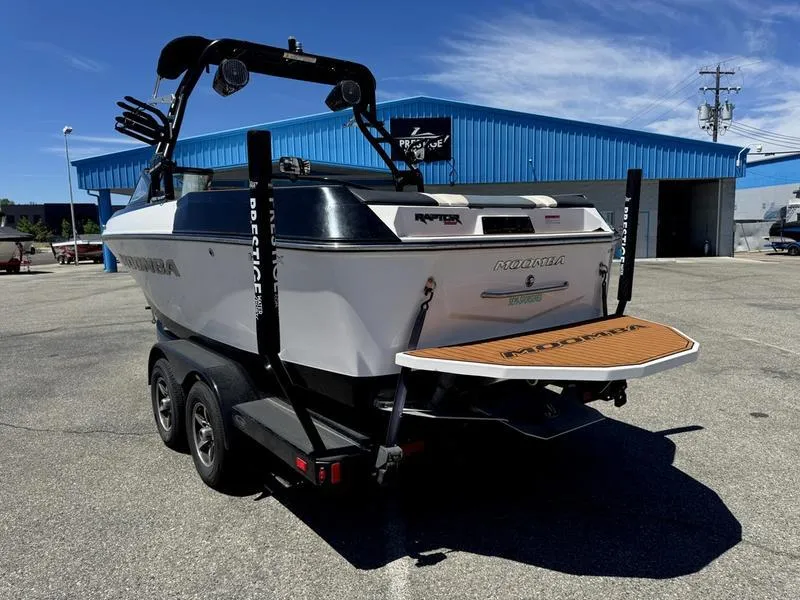 Slide: The Image of 2017 Moomba Helix boat on trailer, parked outside blue building under clear sky. - 5