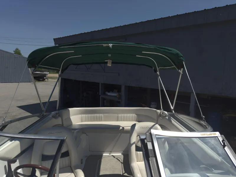 Slide: The Image of 1999 Chris-Craft 210 Bowrider with green canopy, parked outdoors. - 12