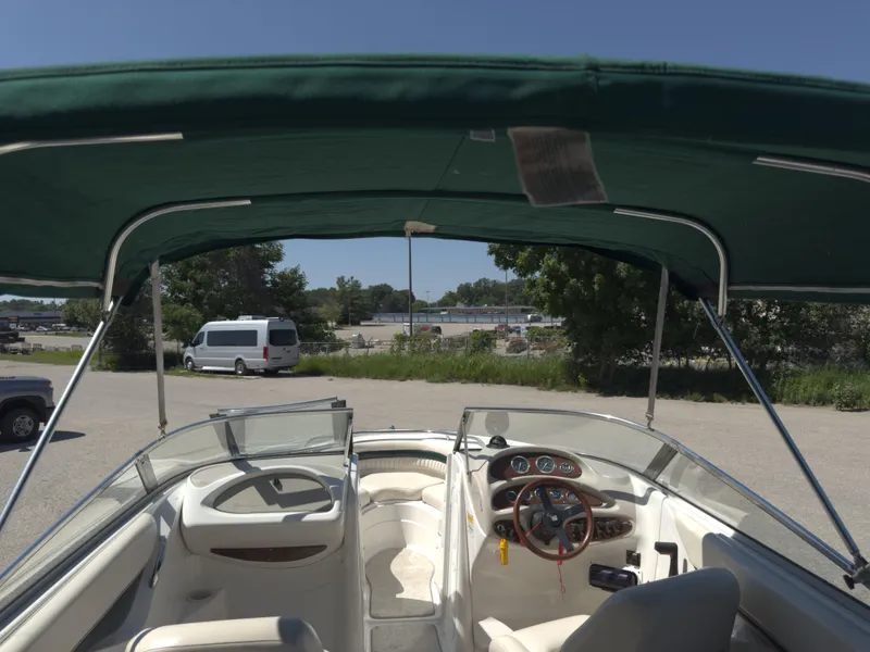 Slide: The Image of 1999 Chris-Craft 210 Bowrider interior with green canopy, parked outdoors. - 13