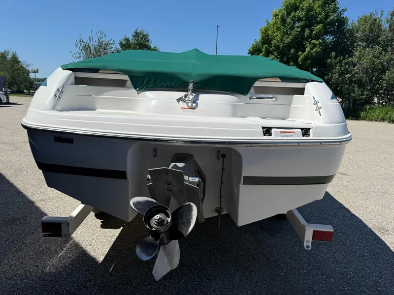 Slide: The Image of 1999 Chris-Craft 210 Bowrider boat with green cover, rear view, parked outdoors. - 3
