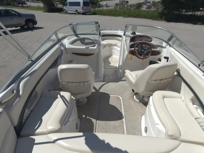 Slide: The Image of 1999 Chris-Craft 210 Bowrider interior with beige seating and steering wheel, parked outdoors. - 6