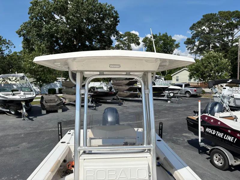 Slide: The Image of 2017 Robalo 226 Cayman boat in a marina with other boats and trees. - 11