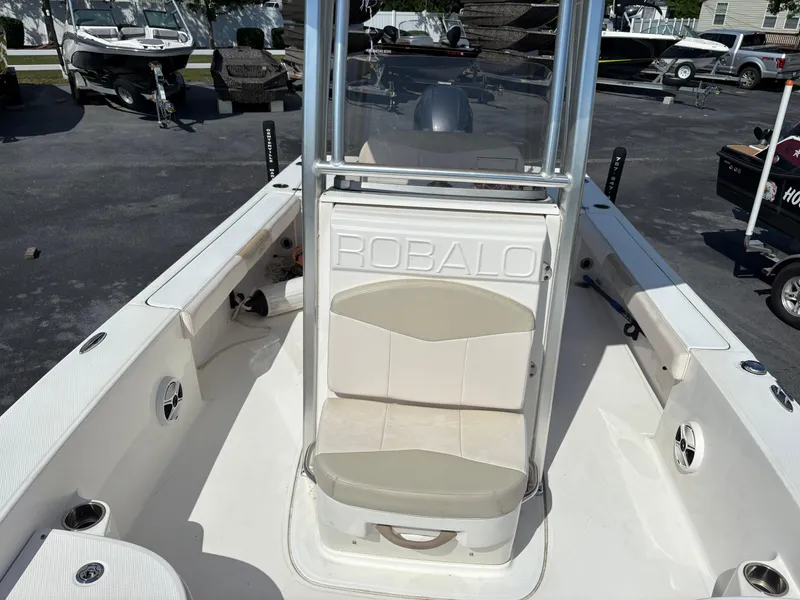 Slide: The Image of 2017 Robalo 226 Cayman boat interior with seating and console, parked in a lot. - 9