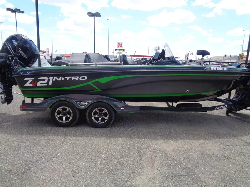 Slide: The Image of 2022 Nitro ZV21 boat with green accents on a trailer in a parking lot. - 4