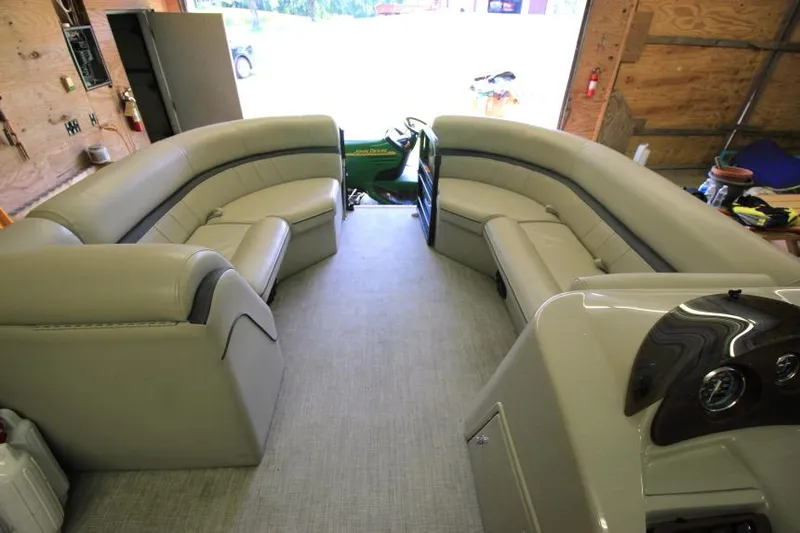 Slide: The Image of 2017 South Bay 222 CR pontoon boat interior with beige seating in a garage setting. - 11
