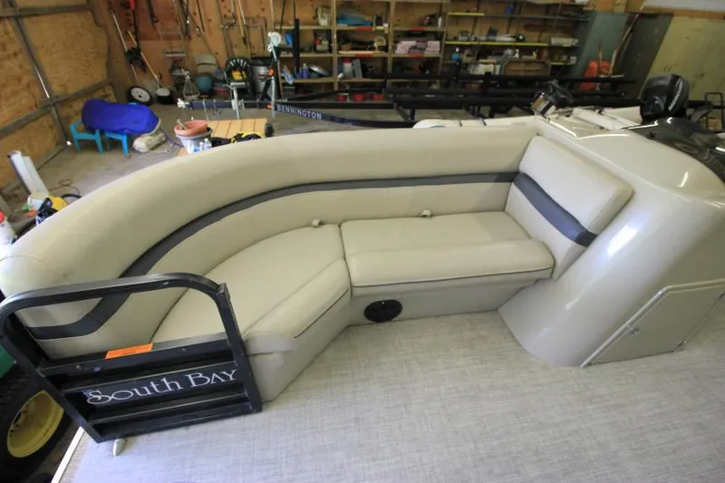 Slide: The Image of 2017 South Bay 222 CR pontoon boat interior with beige seating in a garage setting. - 12