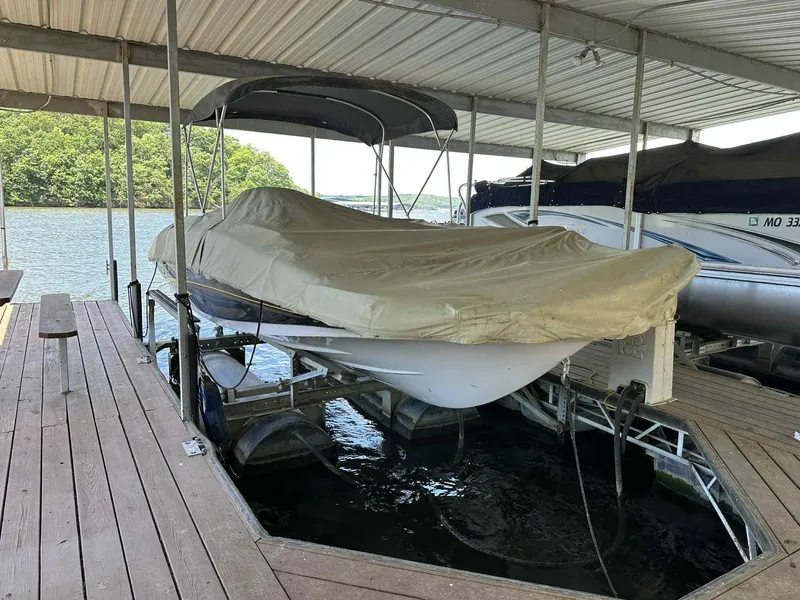 Slide: The Image of Covered 2005 Tahoe 195 OB boat docked under a shelter by the water. - 29
