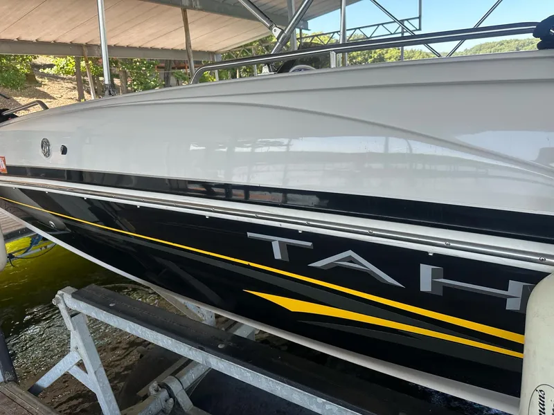 Slide: The Image of 2005 Tahoe 195 OB boat docked under a canopy, featuring sleek black and yellow design. - 31