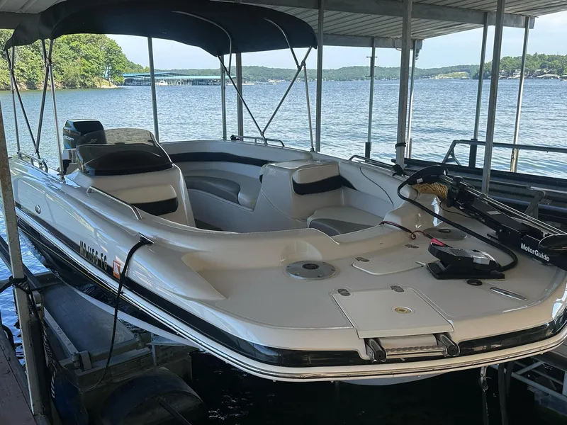 Slide: The Image of 2005 Tahoe 195 OB boat docked on a serene lake under a covered slip. - 32