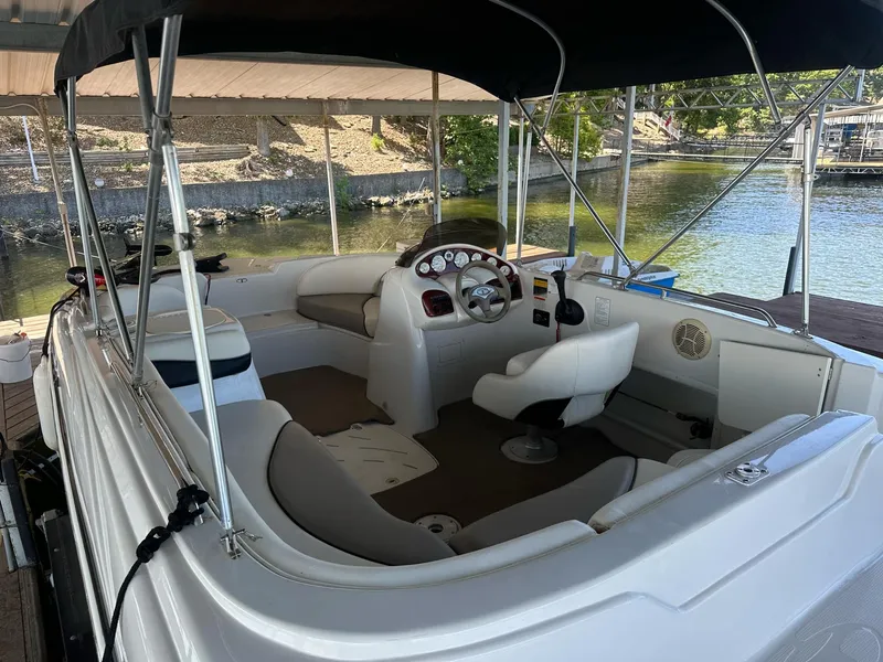Slide: The Image of 2005 Tahoe 195 OB boat interior with seating and steering, docked by a serene lake. - 37