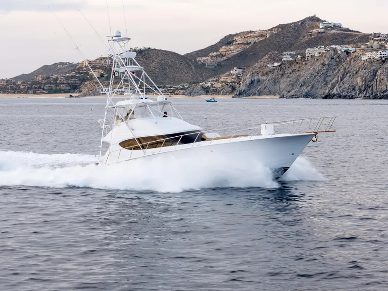 The Image of 2010 Hatteras 60 Convertible yacht cruising near rocky coastline. - 1