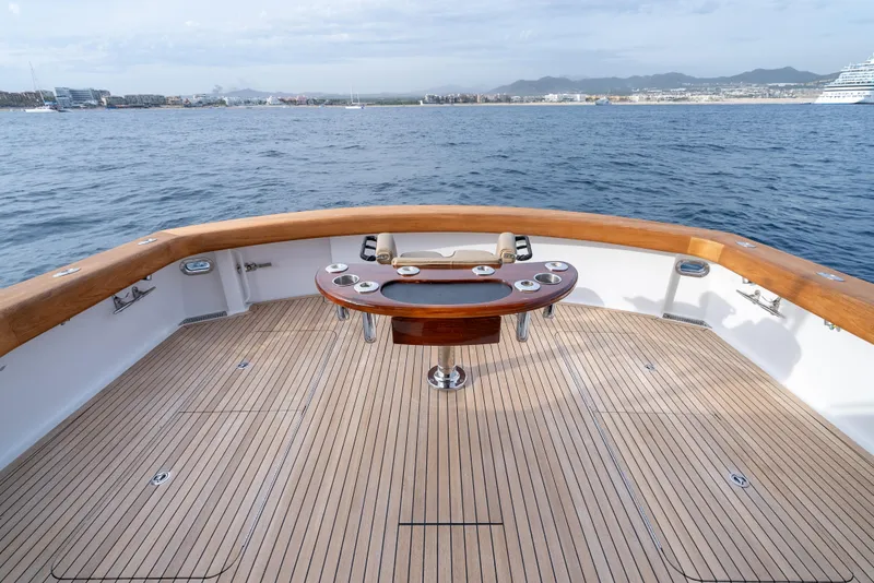 Slide: The Image of Hatteras 60 Convertible 2010 yacht deck with wooden finish, overlooking calm ocean waters. - 12