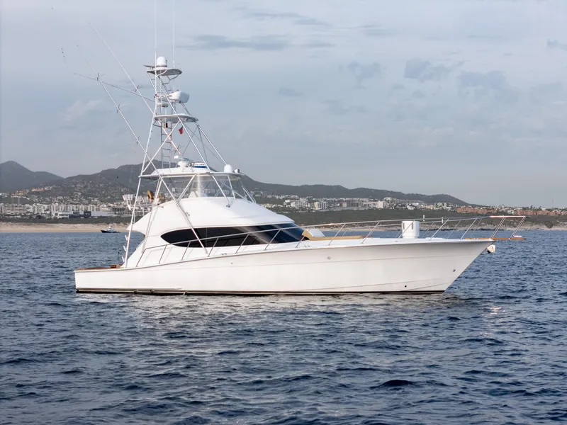 Slide: The Image of 2010 Hatteras 60 Convertible yacht on calm sea with coastal backdrop. - 3
