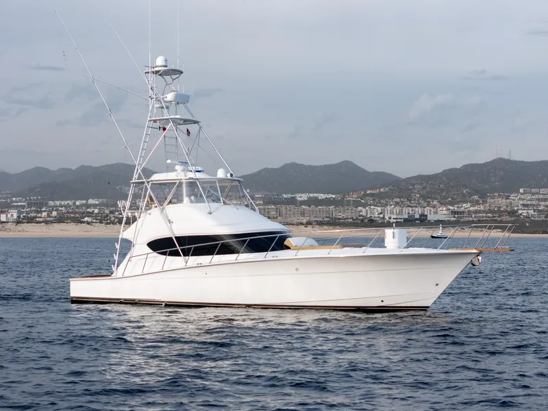 Slide: The Image of 2010 Hatteras 60 Convertible yacht on calm waters with coastal backdrop. - 4