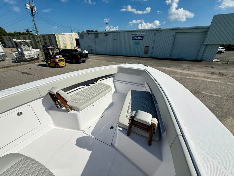 Slide: The Image of 2026 Jupiter 34 boat interior with cushioned seating, parked near industrial buildings under a blue sky. - 13