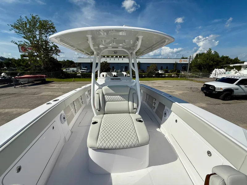 Slide: The Image of 2026 Jupiter 34 boat with sleek seating and canopy, parked outdoors under a blue sky. - 14