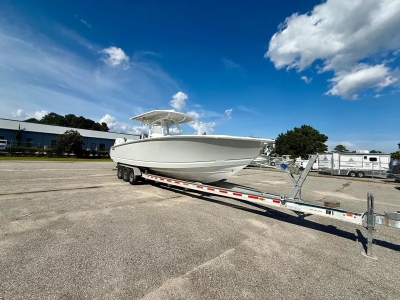 Slide: The Image of 2026 Jupiter 34 boat on trailer under clear blue sky. - 2