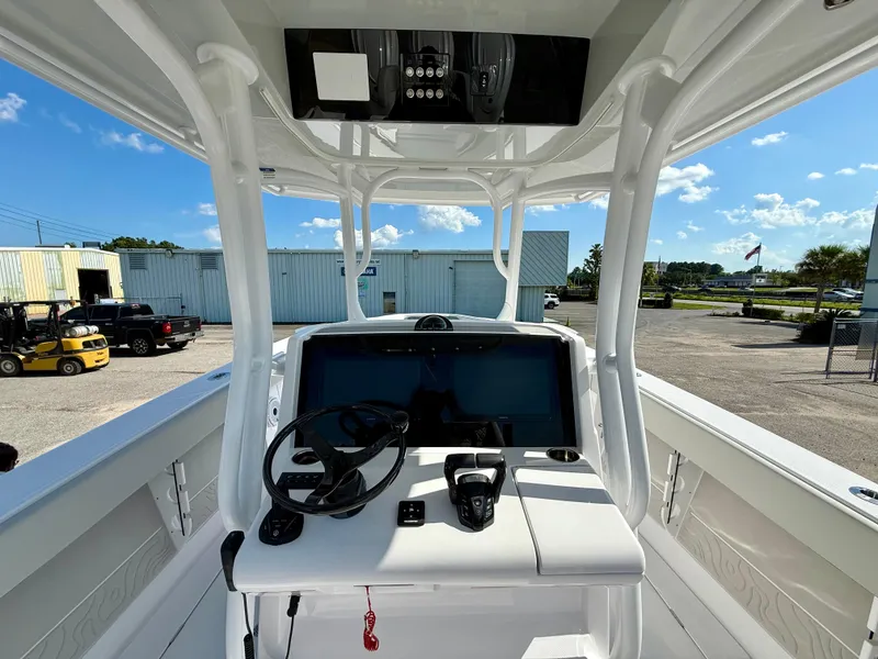 Slide: The Image of 2026 Jupiter 34 boat console with steering wheel and controls, parked outdoors under clear sky. - 8