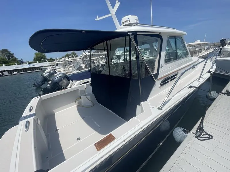 Slide: The Image of 2006 Back Cove 29 boat docked, featuring a covered cockpit and sleek design. - 10