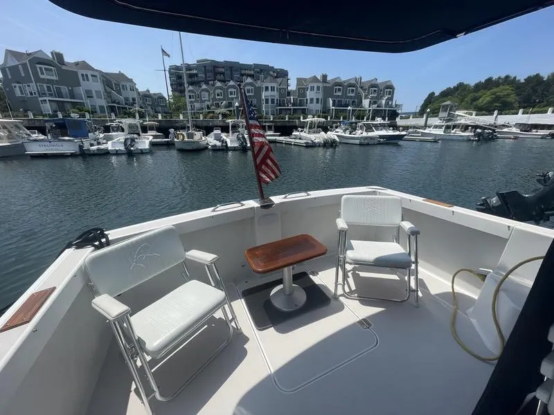 Slide: The Image of 2006 Back Cove 29 boat deck with chairs, table, and American flag in a marina setting. - 11
