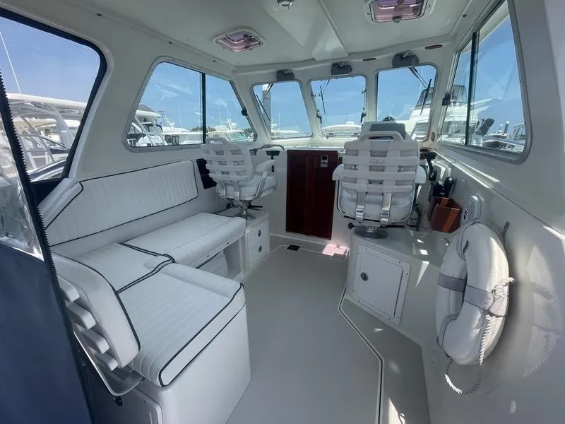 Slide: The Image of Interior of a 2006 Back Cove 29 boat with white seating and helm chairs. - 12
