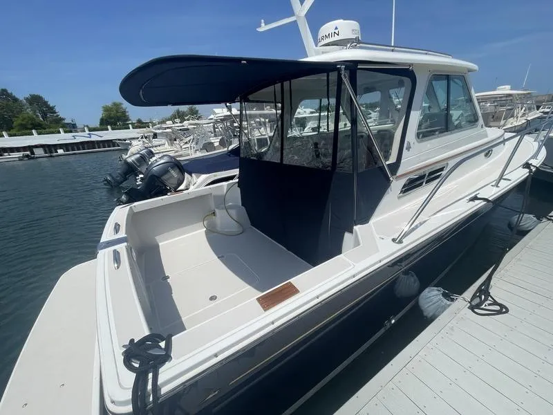 Slide: The Image of 2006 Back Cove 29 boat docked at marina, featuring a covered cockpit and sleek design. - 13