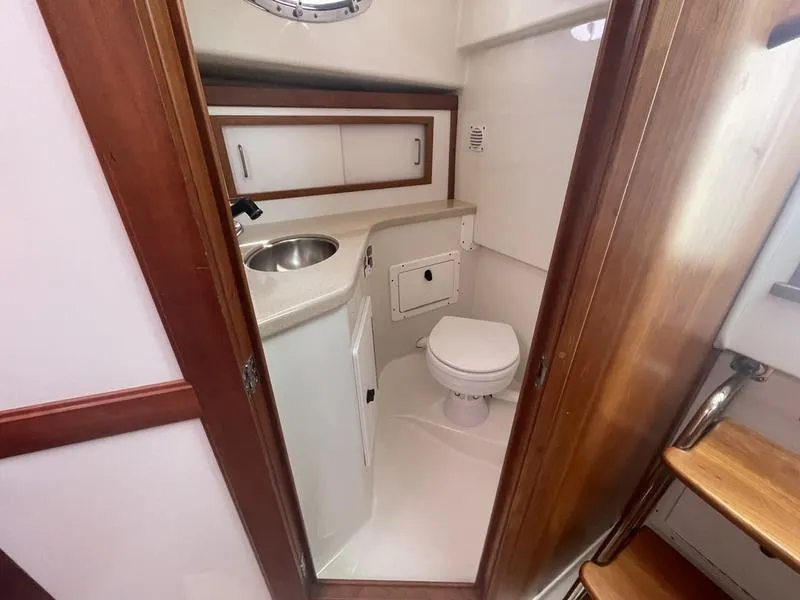 Slide: The Image of 2006 Back Cove 29 boat bathroom with sink, toilet, and wooden accents. - 15