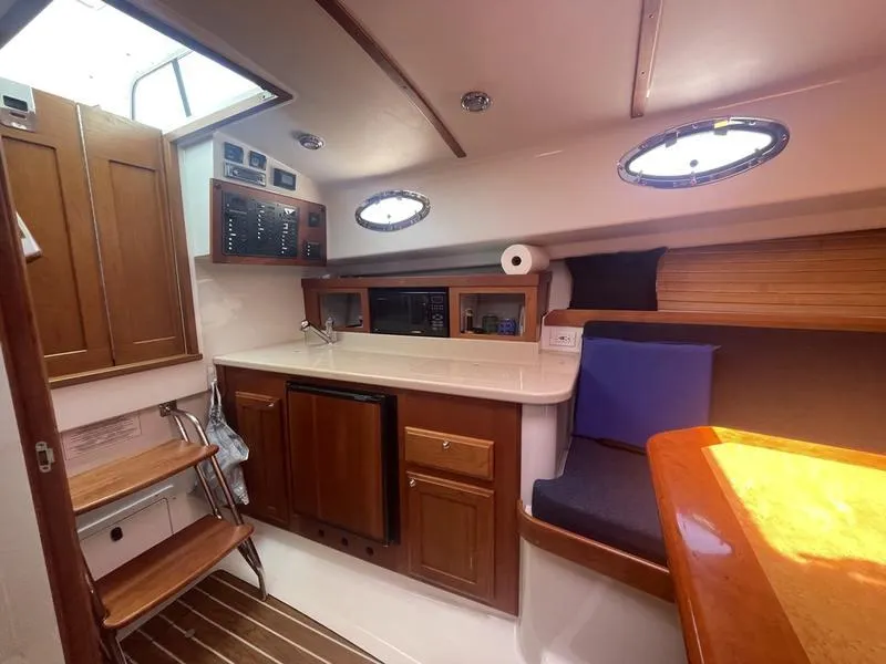 Slide: The Image of Interior of a 2006 Back Cove 29 boat, featuring a compact kitchen and seating area. - 17