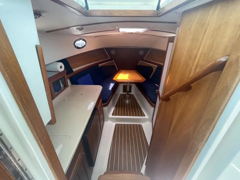 Slide: The Image of 2006 Back Cove 29 boat interior with wood finish, blue seating, and central table. - 19