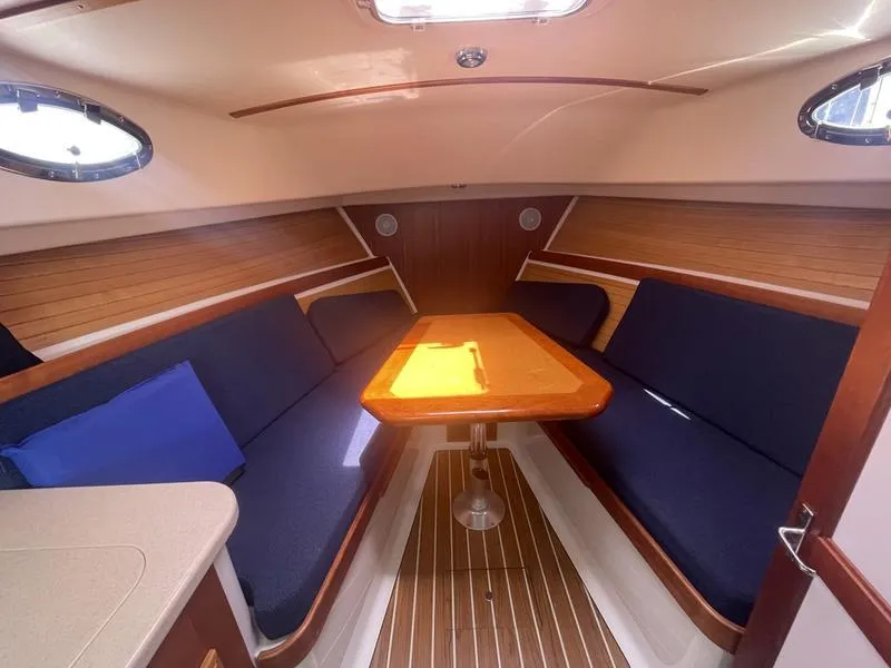 Slide: The Image of 2006 Back Cove 29 interior with wooden table, blue seating, and natural light. - 22