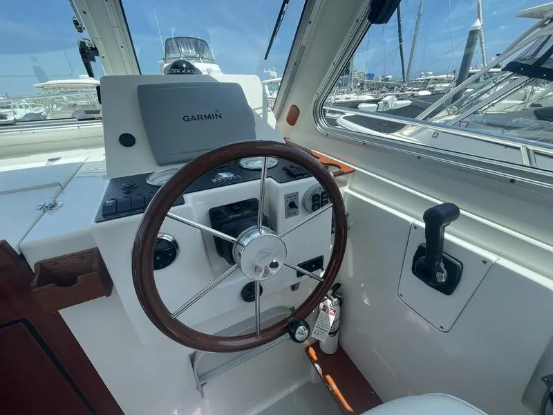 Slide: The Image of 2006 Back Cove 29 boat helm with Garmin navigation, steering wheel, and throttle control. - 24