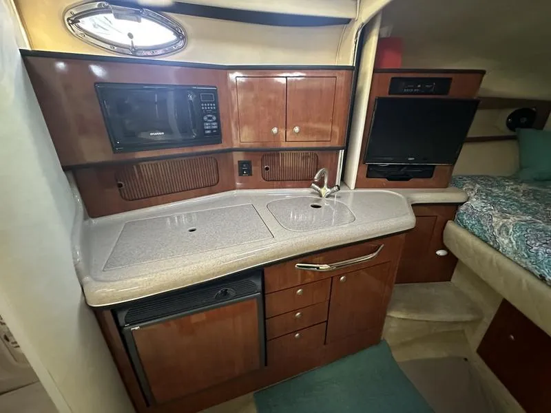 Slide: The Image of 2007 Sea Ray 300 Sundancer interior with kitchenette, microwave, sink, and cozy sleeping area. - 11