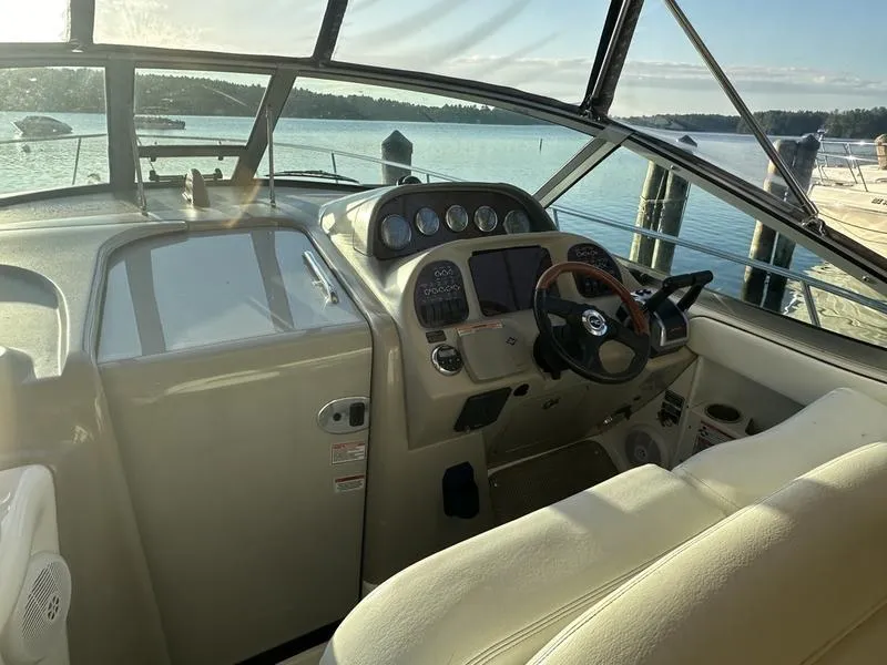 Slide: The Image of 2007 Sea Ray 300 Sundancer helm with steering wheel, gauges, and waterfront view. - 2