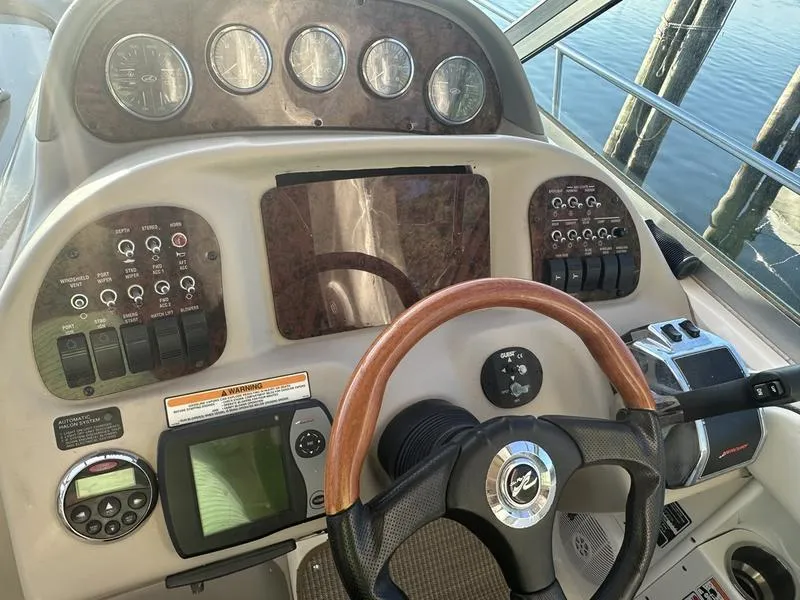 Slide: The Image of 2007 Sea Ray 300 Sundancer helm with gauges, controls, and wooden steering wheel. - 4