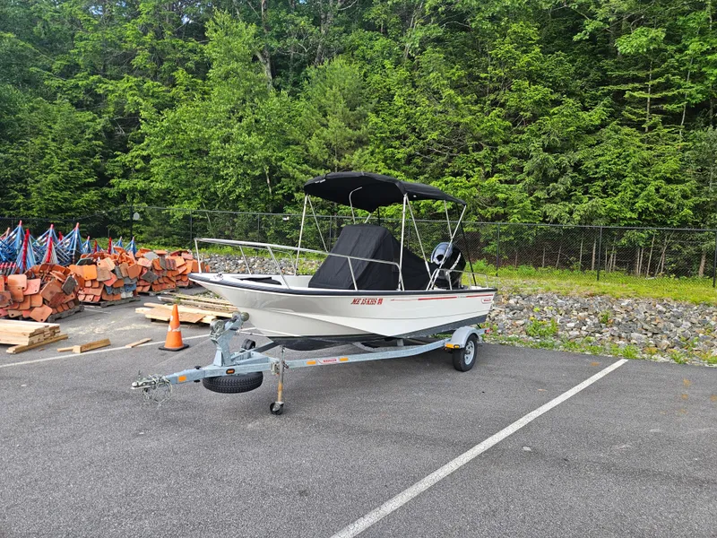 Slide: The Image of 2008 Boston Whaler 170 Montauk boat on trailer in parking lot, surrounded by trees. - 14