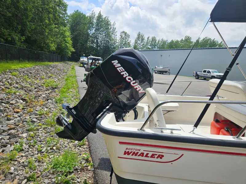 Slide: The Image of 2008 Boston Whaler 170 Montauk with Mercury outboard motor, parked near a rocky path. - 19