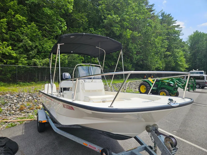 Slide: The Image of 2008 Boston Whaler 170 Montauk boat on trailer, parked near trees and machinery. - 20