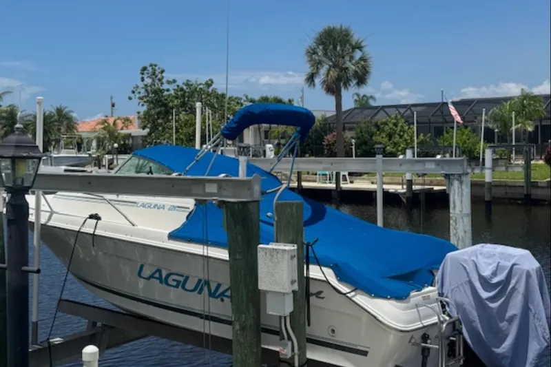 Slide: The Image of 1997 Sea Ray Laguna 21 boat docked, covered in blue tarp, with palm trees in the background. - 9