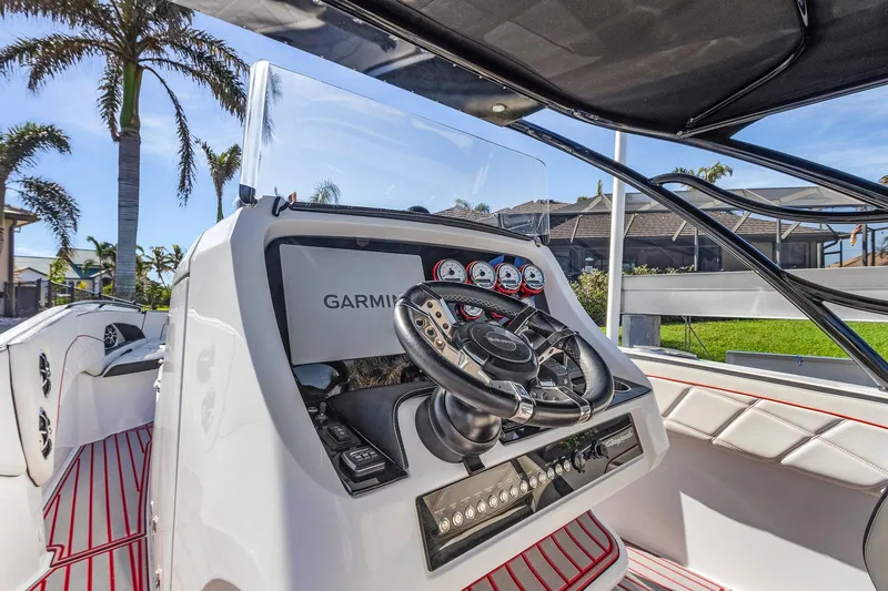 Slide: The Image of 2020 Renegade 33' Open boat dashboard with Garmin navigation, palm trees in background. - 7