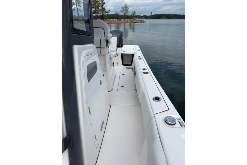 Slide: The Image of 2025 Sea Fox 282 Hybrid LT boat interior with seating and storage, docked on calm water. - 13