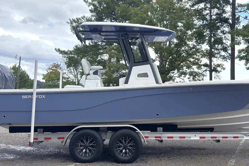 Slide: The Image of 2025 Sea Fox 282 Hybrid LT boat on trailer, side view, blue hull, outdoor setting. - 18